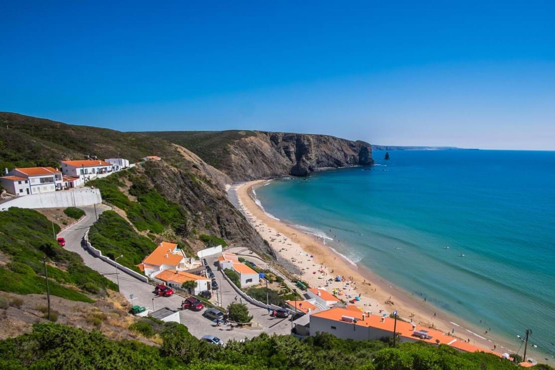 Arrifana, Aljezur, Algarve
Enseada em forma de concha, abrigada do vento e das ondulações que chegam do norte. Tem mais de 700 metros de areal, está envolvida pelas arribas escuras de xisto e fica no concelho de Aljezur, na costa vicentina. Mergulho, pesca, surf e bodyboard são algumas das atividades que podem ser aqui praticadas. O cenário é de filme.