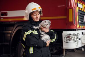 Bombeira segura gato perto de carro dos bombeiros