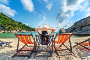 Mulher a relaxar na praia numa cadeira ao sol