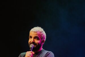 Humorista atua em palco com um microfone