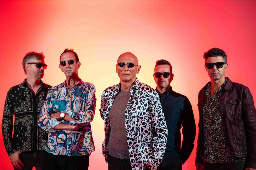 Um grupo de cinco homens posa com óculos de sol e camisas coloridas