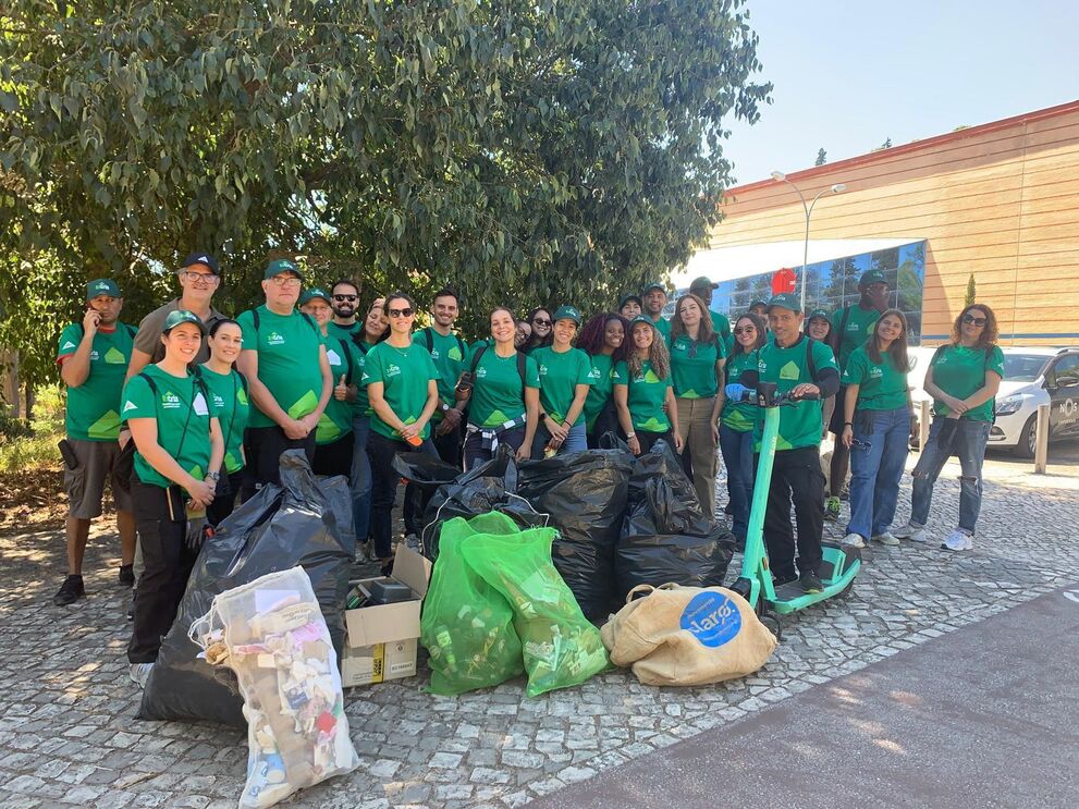 Grupo de pessoas participa numa ação de limpeza ao ar livre com sacos cheios de lixo