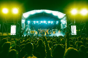 Multidão vibra com a banda em palco num concerto ao ar livre