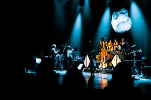 Espetáculo musical com banda e cantores num palco iluminado
