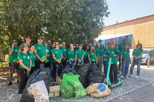 Grupo de pessoas participa numa ação de limpeza ao ar livre com sacos cheios de lixo