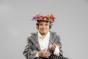 Atriz surge com visual característico, incluindo um chapéu floral