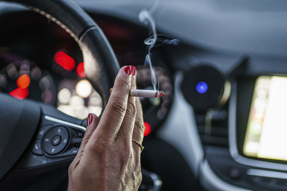 Mulher fuma cigarro enquanto conduz