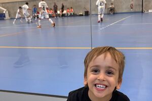 Dinis sorri enquanto assiste a um jogo de futsal, com apoio da Associação Salvador.
