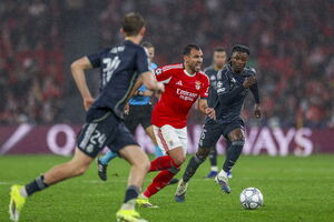 Jogadores do Benfica e Real Madrid disputam a bola sob chuva num jogo de futebol