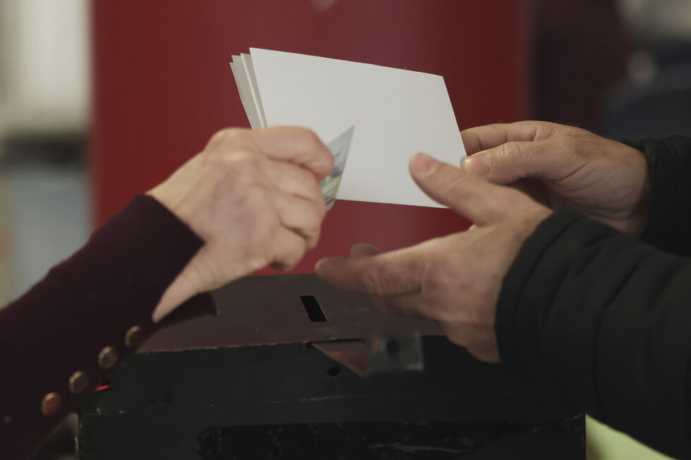 Uma pessoa coloca um boletim de voto numa urna