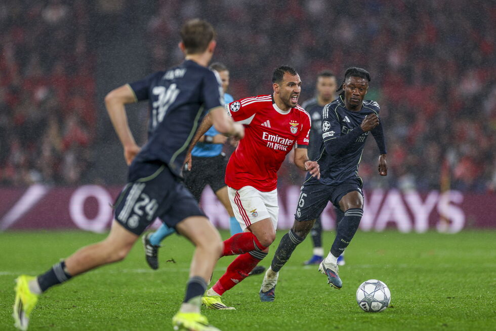 Jogadores do Benfica e Real Madrid disputam a bola sob chuva num jogo de futebol