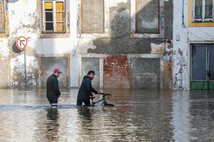 Dois homens atravessam a zona inundada da Ribeira de Santarém