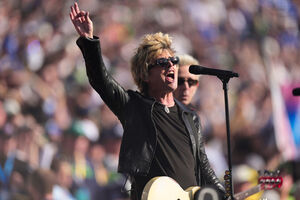 Músico atua no Super Bowl com guitarra e microfone, perante o público