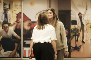 Duas mulheres frente a painéis com imagens de palhaços em contexto hospitalar