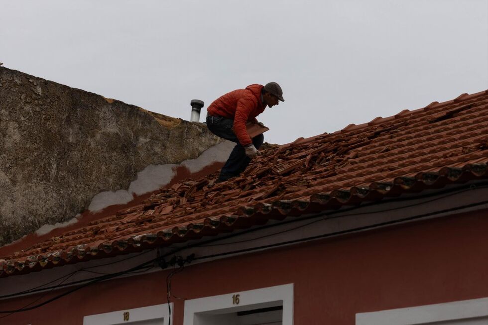 Homem repara telhado danificado pela tempestade Kristin em Portugal