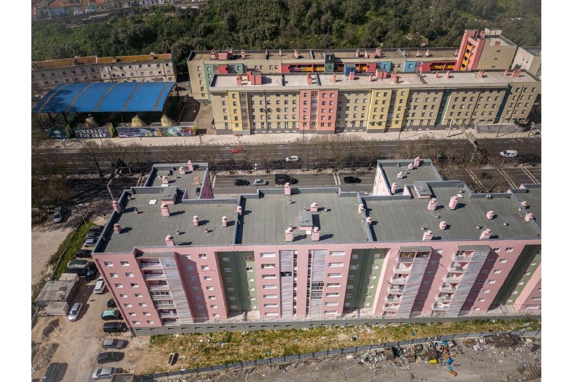 Vista aérea de edifícios coloridos em Lisboa, com tráfego na rua e lixo visível