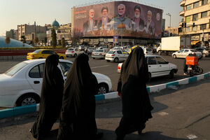Teerão: Mulheres caminham junto a cartaz com figuras políticas