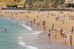 Praia cheia de pessoas em dia soalheiro, com temperaturas a atingir os 26 graus.
