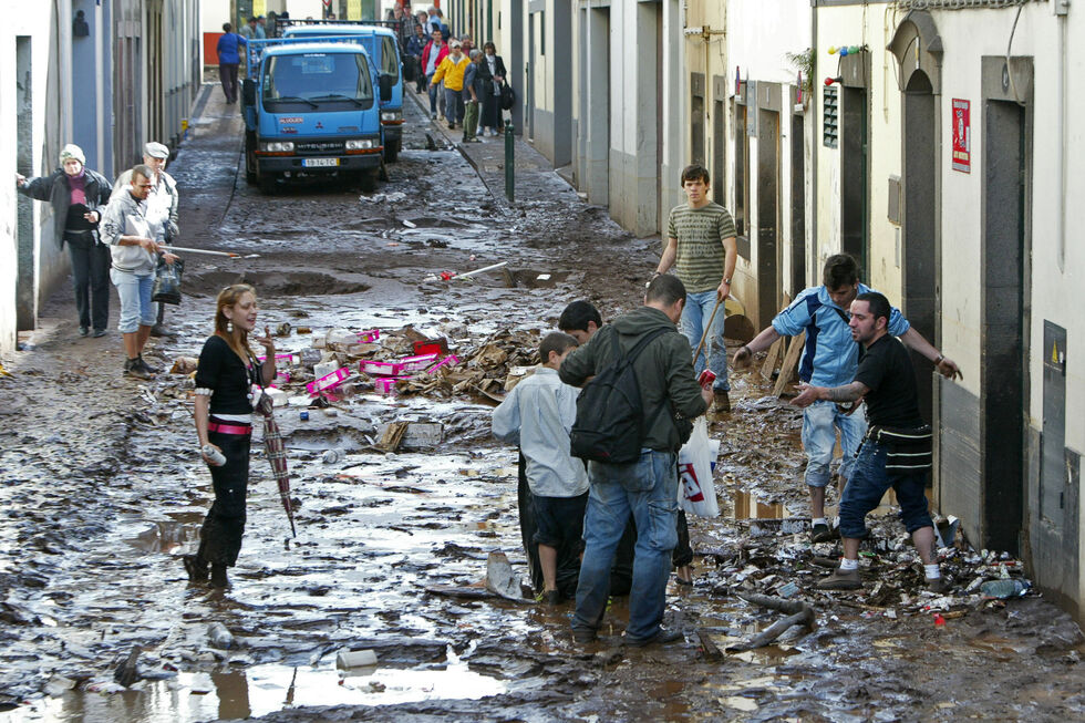 Populares e bombeiros limpam as ruas inundadas devido ao mau tempo que ocorreu na Madeira