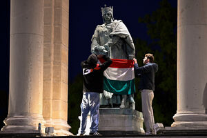 Manifestantes exibem bandeira da Hungria em frente à estátua de Rei André I, em Budapeste