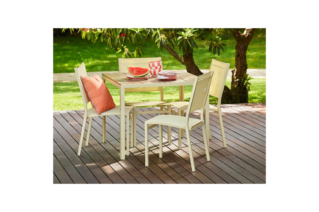 Mobiliário de exterior num deck de madeira com melancia e louça sobre a mesa