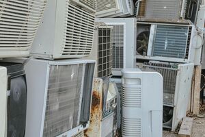Vários aparelhos de ar condicionado amontoados, alguns com ferrugem