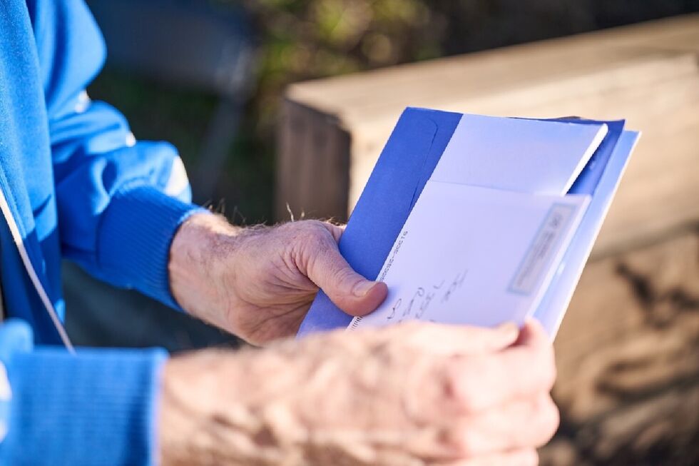Homem lê correspondência com envelope azul e conteúdo branco