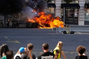 Pessoas observam um carro em chamas durante uma manifestação "Não ao G7"