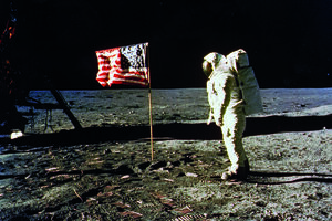 Um Passo na Lua, 1969 - Buzz Aldrin junto à bandeira norte-americana na superfície lunar, durante a missão Apollo 11, a primeira a levar seres humanos  à Lua. Fotografia de Neil Armstrong com a data de 20 de julho de 1969. A imagem e a frase de Armstrong, “um pequeno passo para o homem,  um salto gigante para  a humanidade”, marcaram  a conquista. 