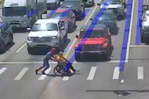 Homem vestido de Homem-Aranha ajuda pessoa em cadeira de rodas a atravessar a rua