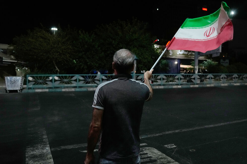 Manifestante pró-governo acena com uma bandeira iraniana