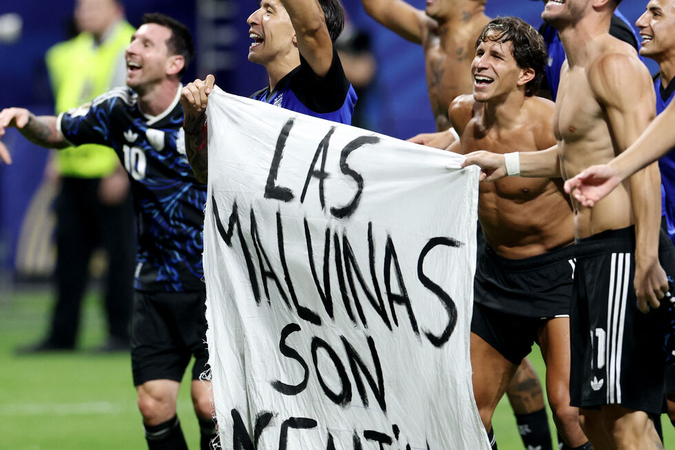 Jogadores de futebol celebram com uma bandeira que diz "Las Malvinas son Argentinas"