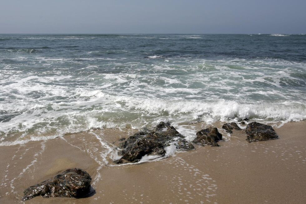 O mar bate nas rochas numa praia de areia