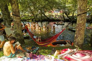 A água fria do rio Coura não demove milhares de festivaleiros, que ali combatem o calor