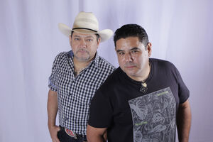 Dois homens em estúdio, um com chapéu de cowboy e outro com t-shirt com estampado de folhas