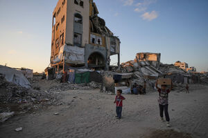 Crianças caminham entre as ruínas de edifícios destruídos por ataques aéreos israelitas