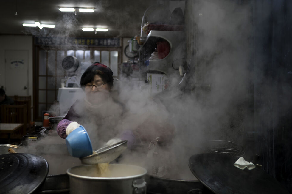 Mulher na Coreia do Sul prepara sopa num restaurante