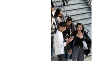 Estudantes em escadas, um a mostrar o telemóvel a outros