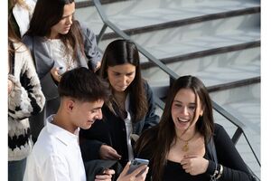 Estudantes em escadas, um a mostrar o telemóvel a outros