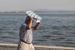 Homem protege-se do calor com um saco de papel