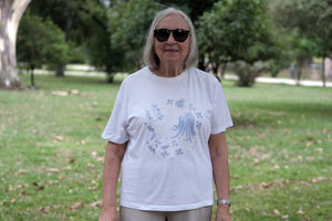Mulher idosa com óculos de sol e t-shirt com flores azuis num parque
