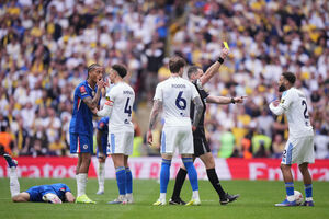 Referee Jarred Gillett a yellow card to Leeds' Jayden Bogle, right, during the FA Cup semifinal soccer match between Chelsea