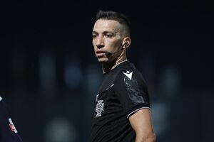 O árbitro em ação no relvado durante o jogo. Costas