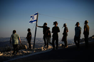 Um grupo de colonos ergue uma bandeira de Israel