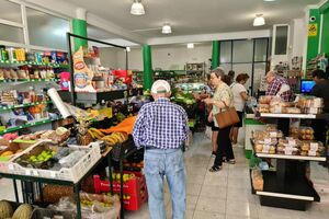 Pessoas a fazer compras num supermercado com frutas e pão