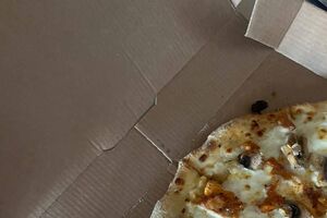 Pizza com cogumelos e frango numa caixa de cartão
