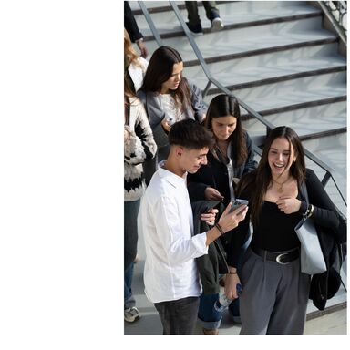Estudantes em escadas, um a mostrar o telemóvel a outros