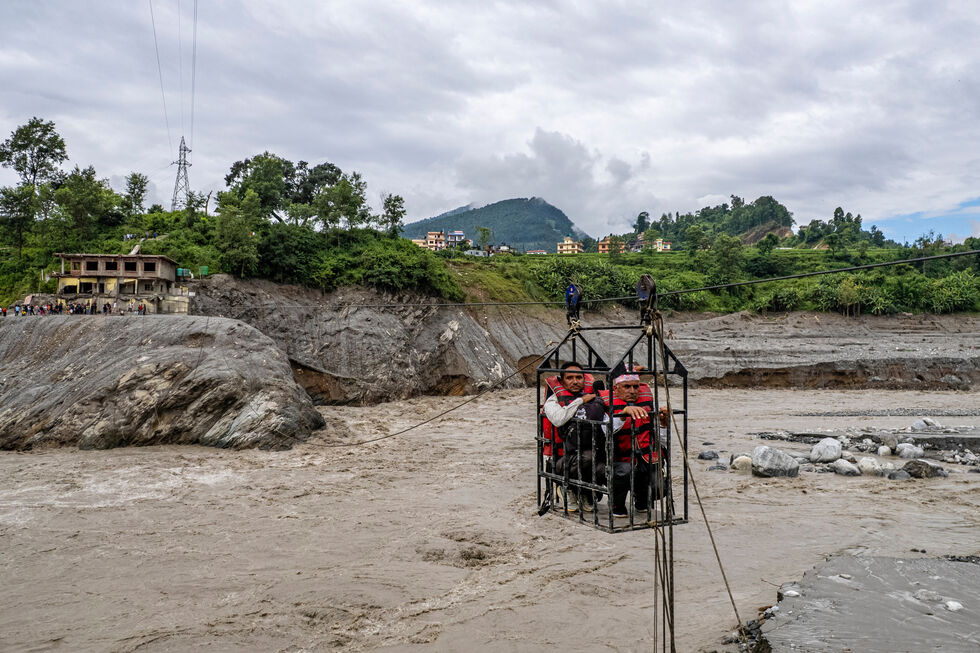 Residentes atravessam o rio Trishuli na sequência das cheias repentinas ocorridas em Bidur, Nepal
