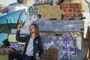 Manifestante em Lisboa com cartazes "O povo sem moedas" e "Ele quer-te na rua mas calado"