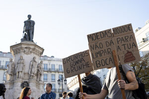 Manifestantes com cartazes sobre Moedas 